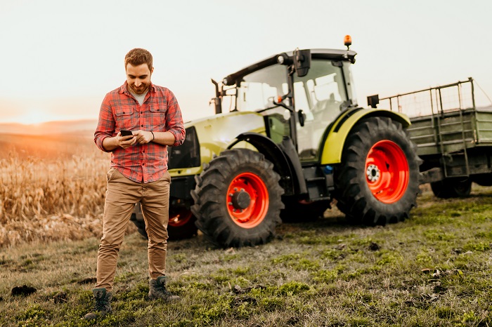 Male farmer working on field using smartphone in modern agricult